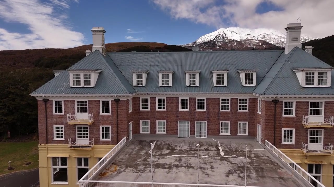Facade of Chateau Tongariro Historic Hotel in Tongariro National Park, New Zealand. Aerial drone low flight