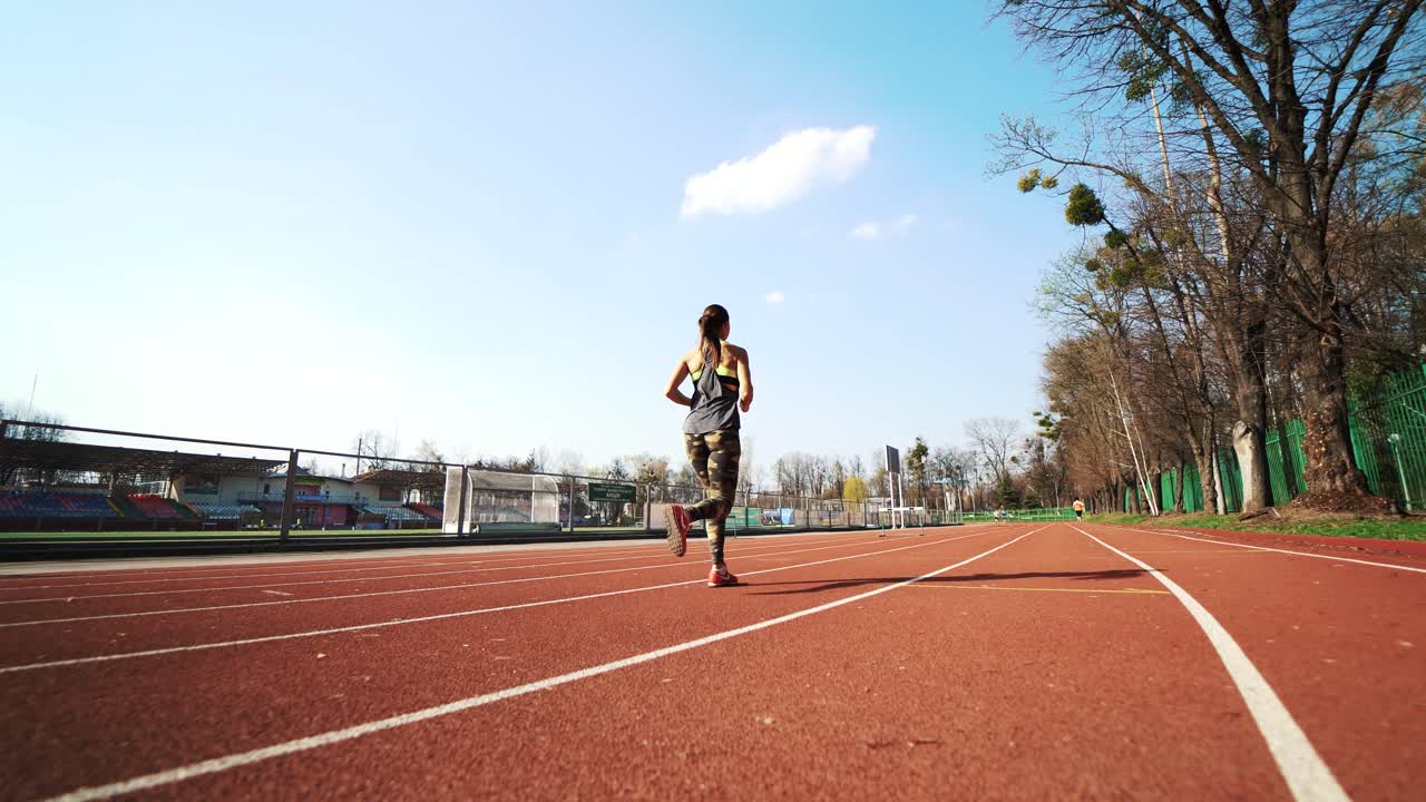Young athletic woman running on stadium track. Beautiful body. Healthy fitness lifestyle