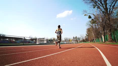 young athletic woman running on stadium track. beautiful body. healthy fitness lifestyle