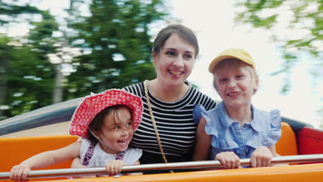 Feliz-Joven-Madre-Con-Dos-Hijas-Cabalgando-Sobre-Un-Columpio-En-El-Parque-1