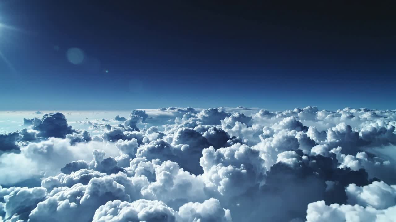 Gliding camera approaching cumulus tops over clouds to reveal sunlit texture and blue sky