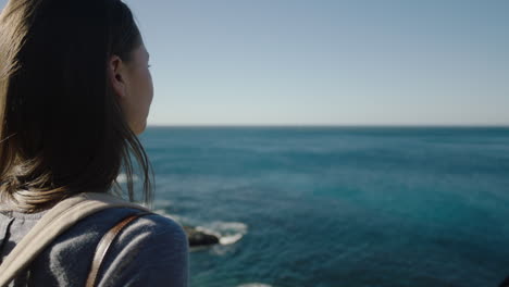 close up of young adventurous woman looking at beautiful ocean seaside view enjoying successful vacation travel running hand through hair