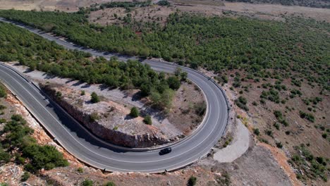 Isolated-car-driving-on-beautiful-curved-road-on-mountain-terrain,-travel-concept