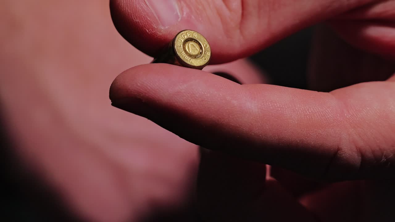 Uomo che fa rotolare lentamente una cartuccia di munizioni vere tra le dita come deterrente