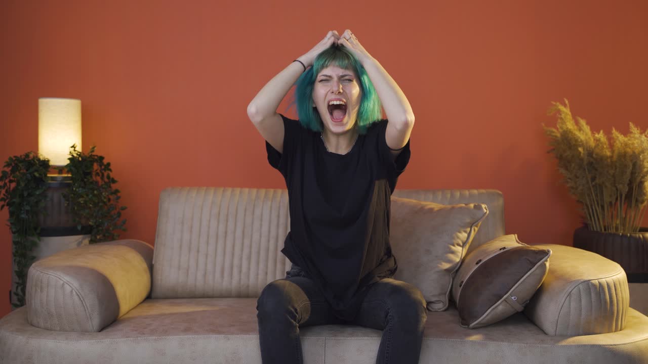젊은 여자는 집에서 분노로 비명을 지르고 있습니다.