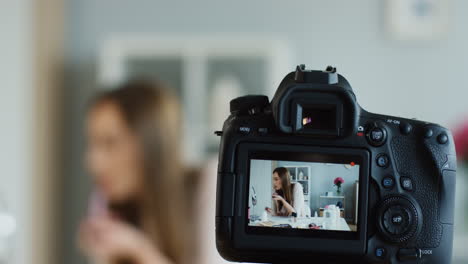 primer plano de la pantalla de la cámara mientras la joven bloguera de belleza graba un video y se pone lápiz labial