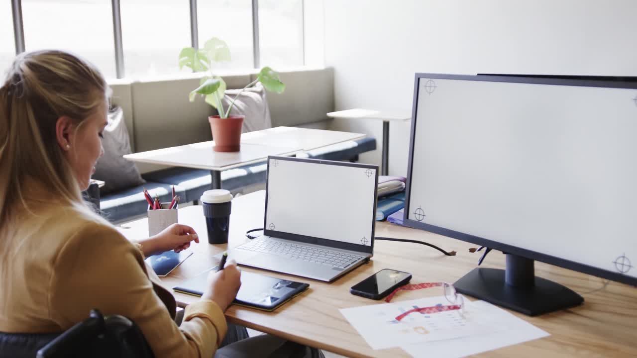 mujer de negocios caucásica en silla de ruedas usando computadora portátil y computadora con espacio de copia, en cámara lenta