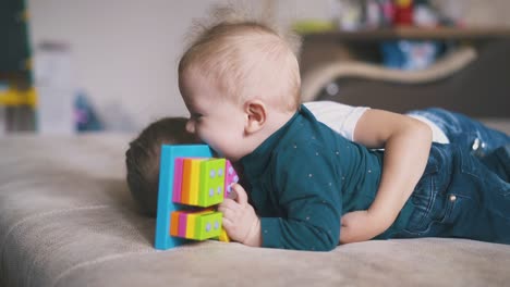 Glückliches-Mädchen-Umarmt-Kleinen-Bruder-Mit-Lustigem-Spielzeug-Auf-Großem-Bett