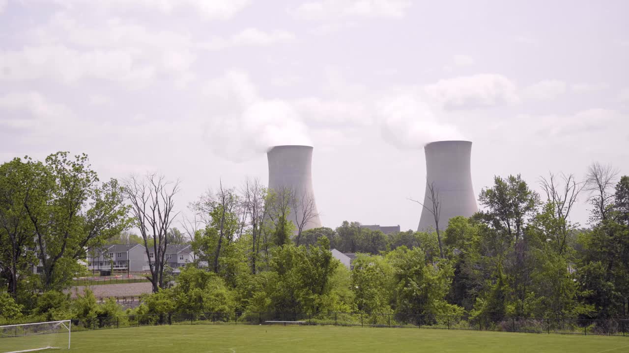 Nuclear Power Plant on a warm cloudy day with steam rising in a suburban neighborhood with a soccer field