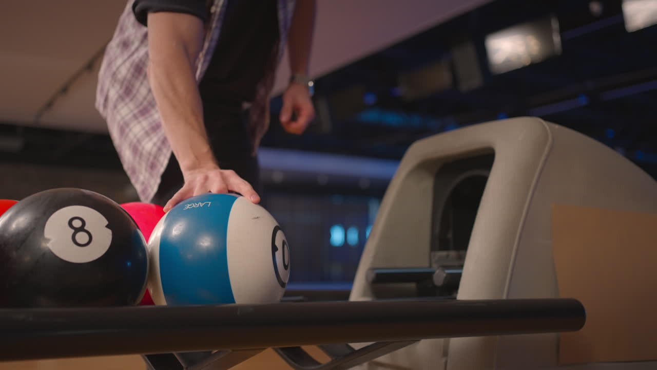 A man in a bowling club picks up a bowling ball with the number 10 in slow motion. Preparation for a throw in bowling