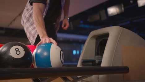 a man in a bowling club picks up a bowling ball with the number 10 in slow motion. preparation for a throw in bowling