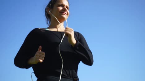 Sporty-girl-running-against-blue-sky