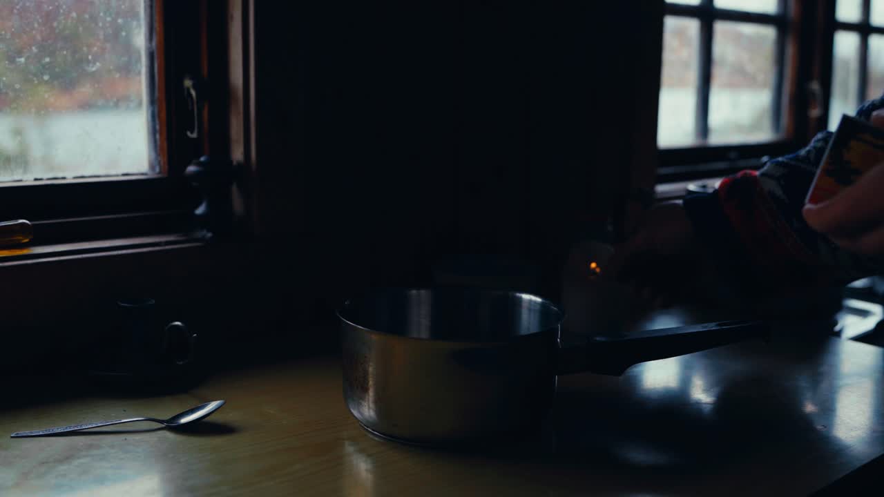 A Person Lit A Candle With A Pot In A Dark Kitchen Countertop. Close-up Shot