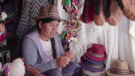 medium shot of traditional woman (cholita) weaving in the recoleta market, sucre