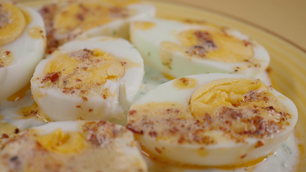 Close-up of Hard-Boiled Eggs with Creamy Sauce and Spices on a Plate