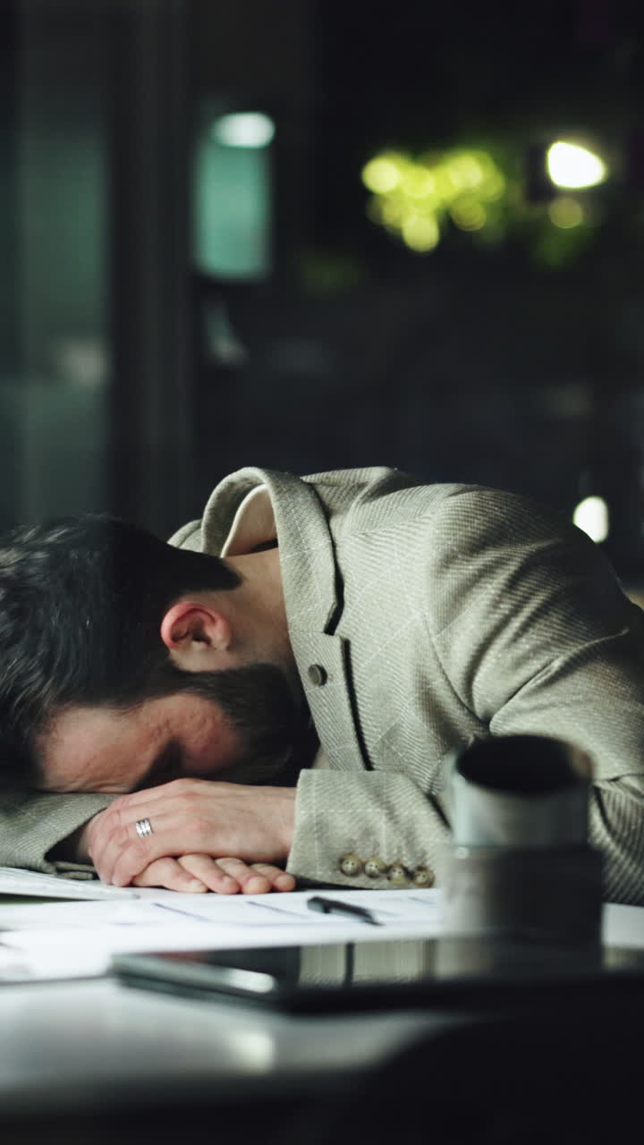 Uomo stanco con la testa appoggiata sulla scrivania, che sembra sovraccarico di lavoro