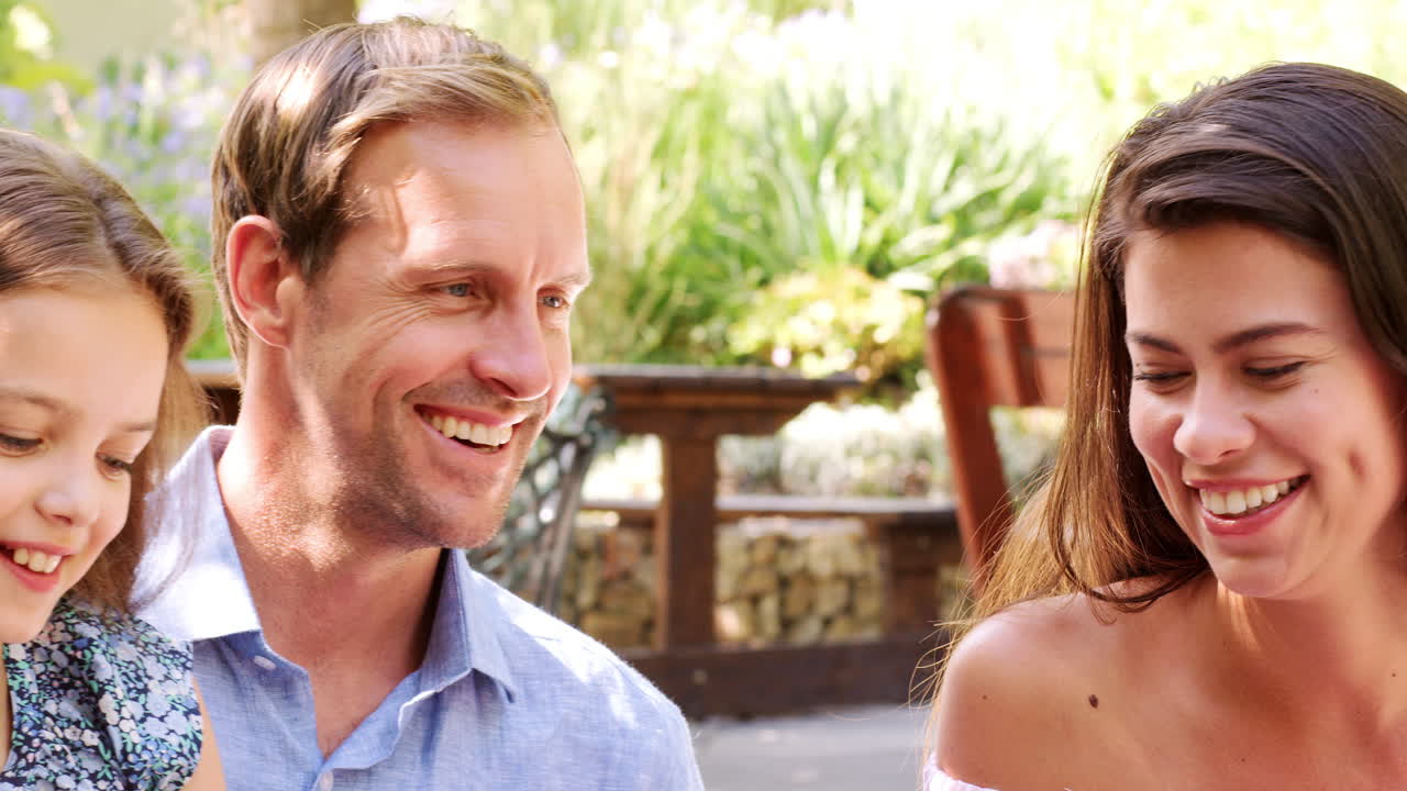 젊은 백인 가족이 카페 밖에서 점심을 먹고 있다