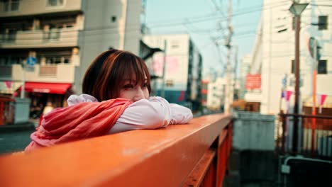 woman leaning on a bridge in a city