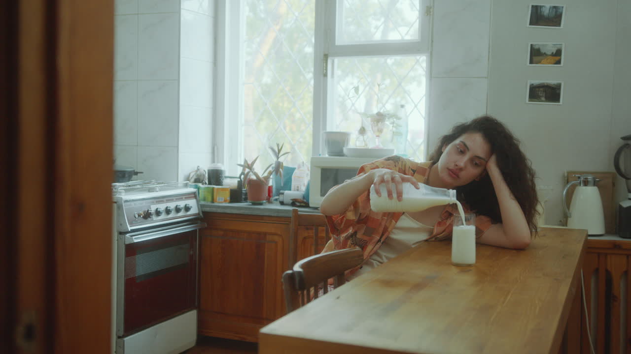 우울한 소녀가 집에서 외로운 날 부에서 유리잔에 우유를 부어