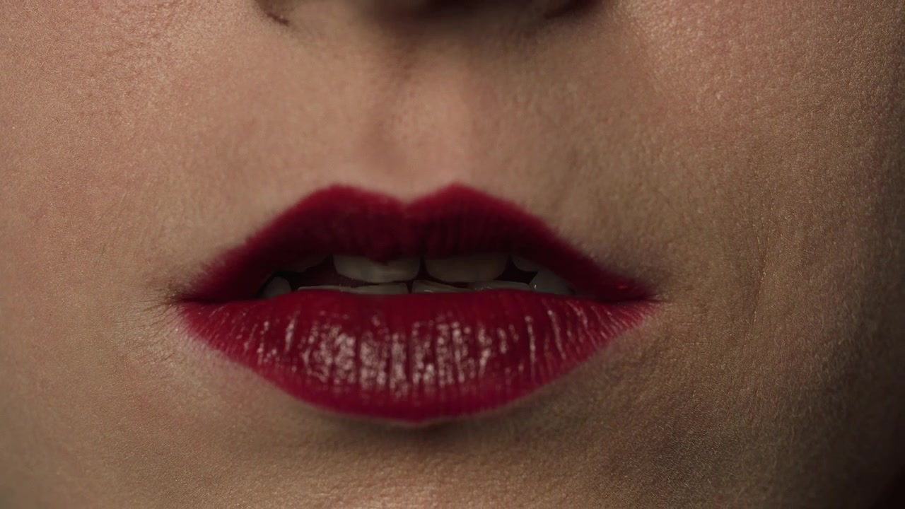 Close de mulher aplicando batom vermelho escuro