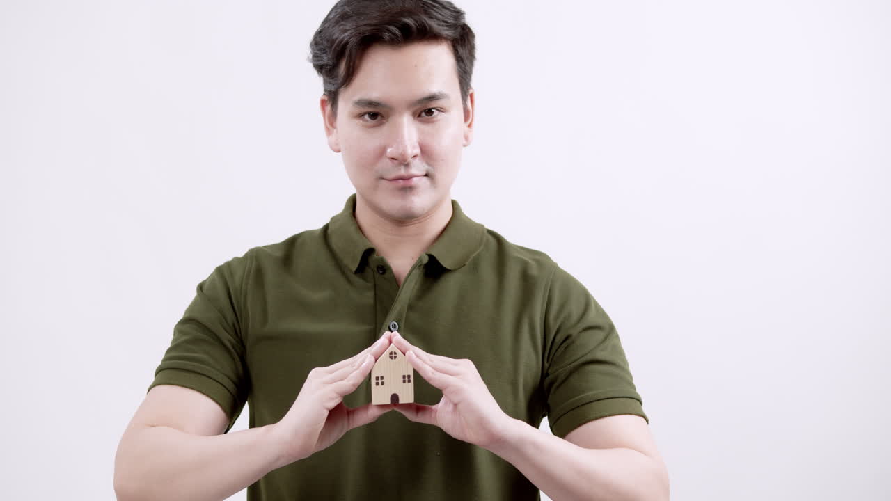 A real estate expert confidently presents a miniature house in a contemporary studio setting.