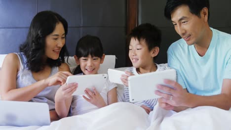Happy-family-using-electronic-devices-in-bedroom-4k