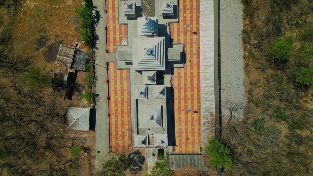 Una ripresa cinematografica con drone in avvicinamento e movimento dall'alto verso il basso sopra lo Shree Vindhyavaasini Devi Mandir a Dindori, Nashik, che rivela l'architettura del tempio, la vegetazione e un ambiente spirituale sereno in 4K.