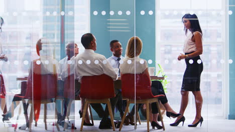 female boss stands addressing colleagues at business meeting