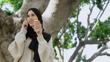 woman in hijab having coffee while talking on mobile phone 4k