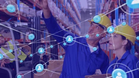 Animation-of-network-of-icons-over-caucasian-male-and-female-worker-checking-stock-at-warehouse