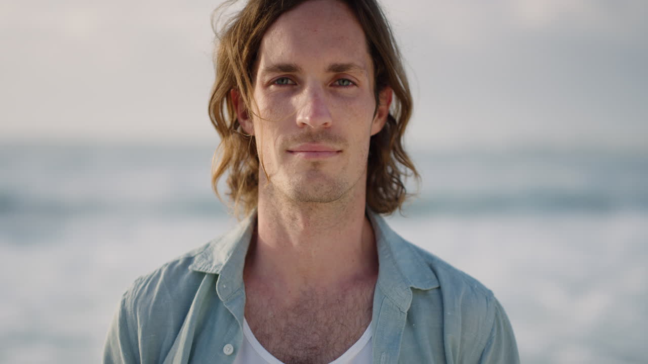 retrato de un apuesto hombre caucásico disfrutando de una tranquila playa costera mirando a la cámara vacaciones de verano