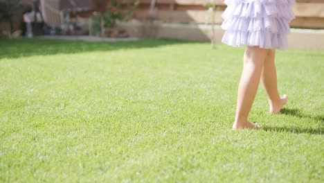 a little girl in a dress is blowing soap bubbles in the backyard on a sunny summer day