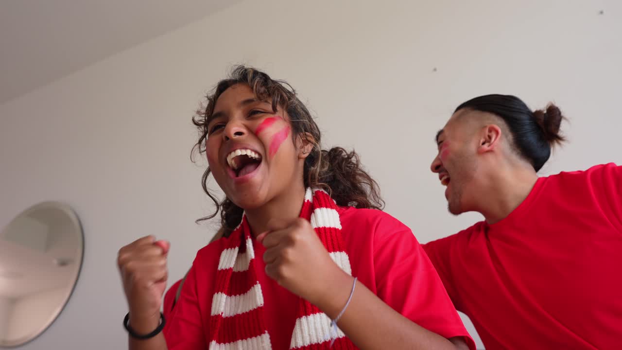 Begeisterte Fußballfans jubeln und feiern ein Tor zu Hause.