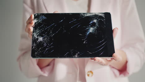 a woman holds a tablet with a broken screen