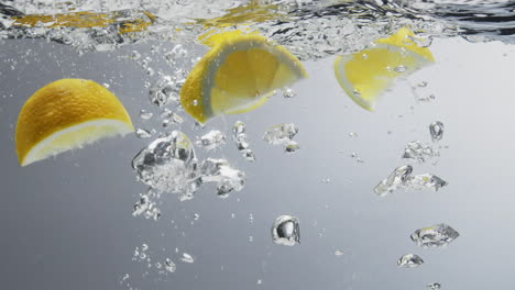 Lemon-quarters-falling-into-fresh-clear-water-with-bubbles