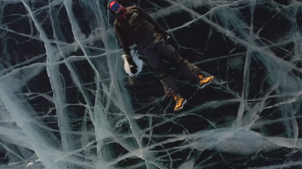 un hombre yace en el hielo en invierno, balanceando sus brazos y piernas hacia un lado, fingiendo que está nadando en el agua.