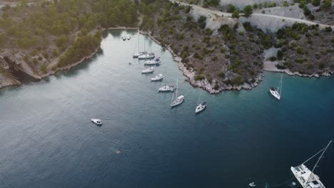 high altitude drone orbit view of a wild secluded beach at the coastline of brac island, croatia, adriatic sea, where luxury sailing boats are anchored