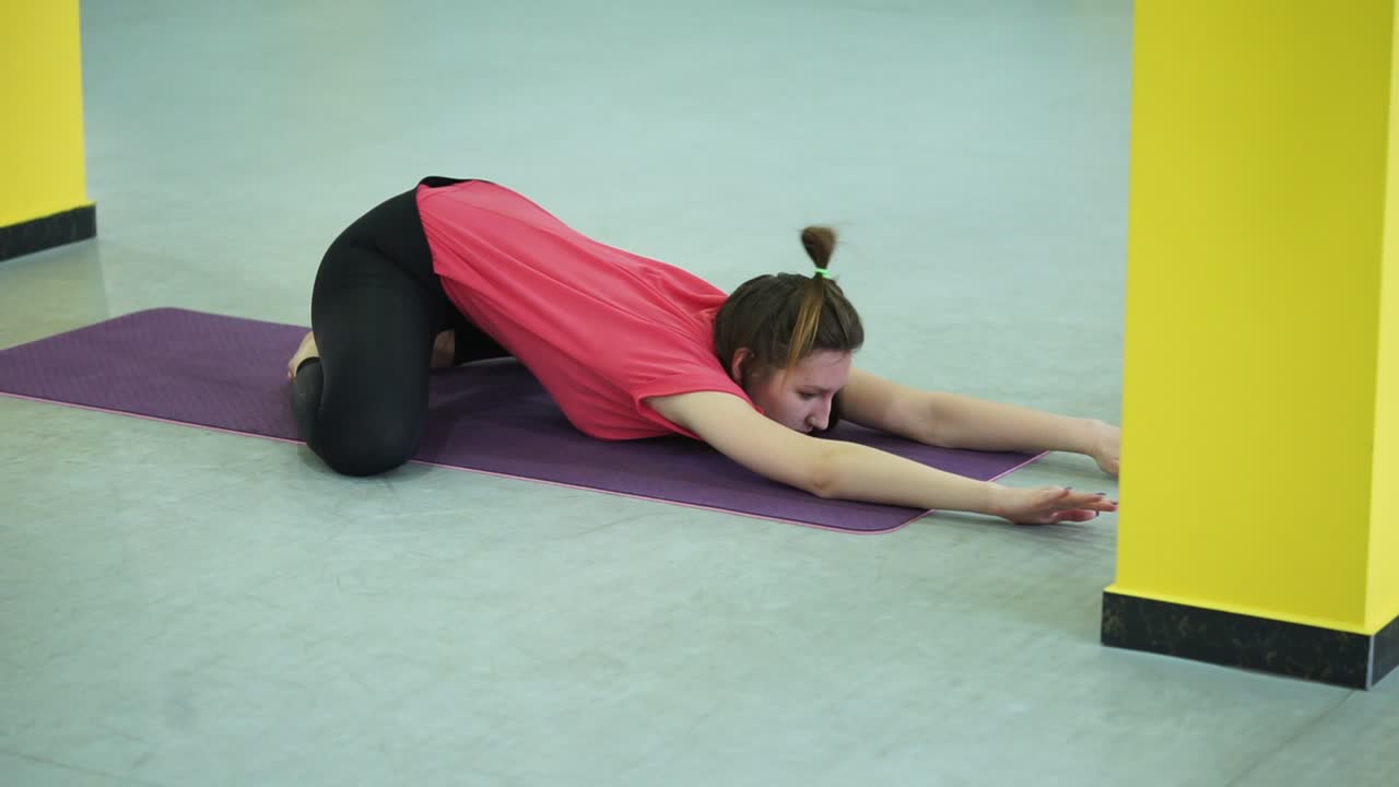 mujer realizando una postura de yoga inclinada hacia adelante sentada
