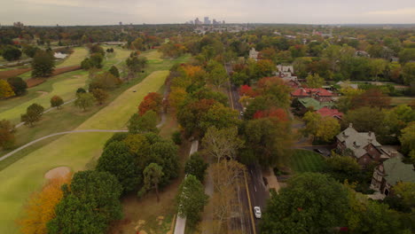 Aerial-over-Lindell-Blvd-with-a-tilt-up-to-reveal-the-Clayton-city-skyline-on-the-horizon-on-a-beautiful-Fall-day,-camera-booms-down-towards-street-level