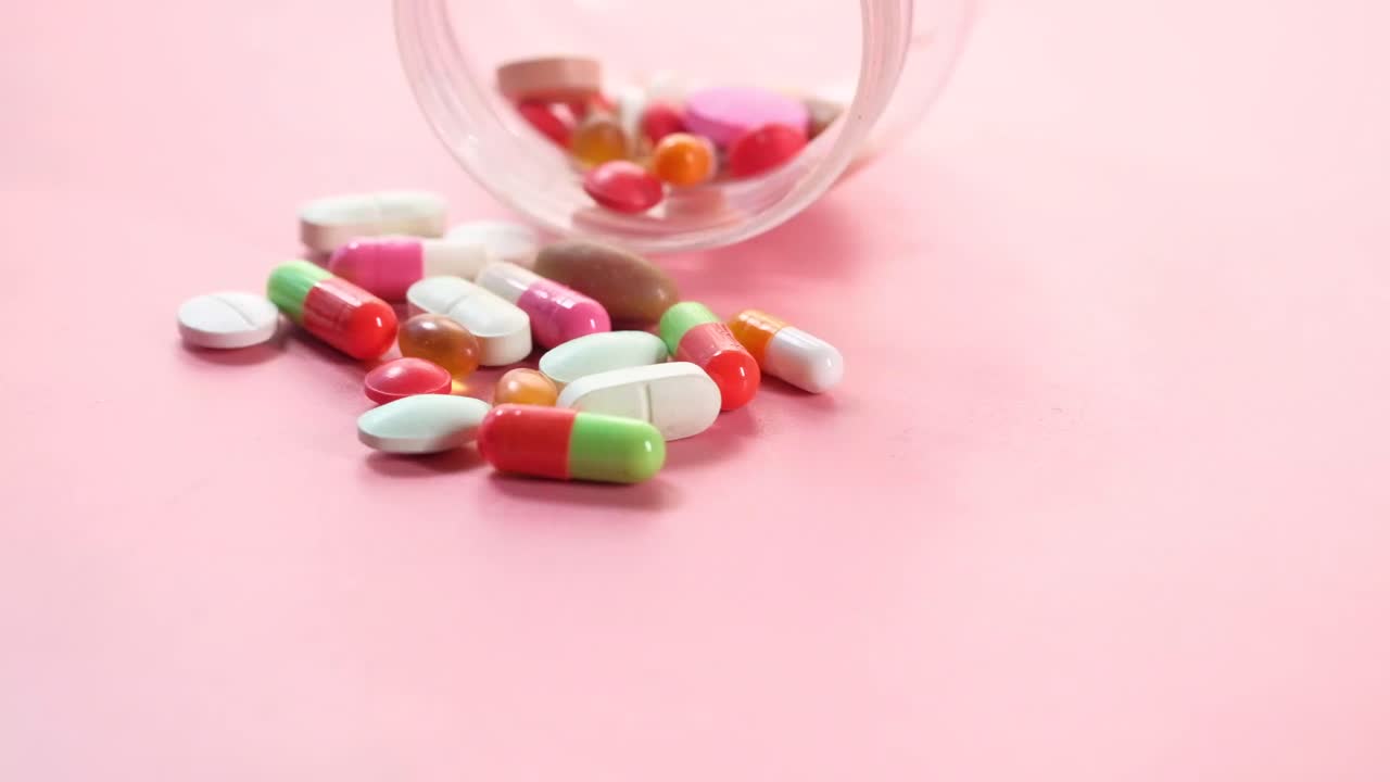 pastillas y cápsulas variadas sobre un fondo rosado