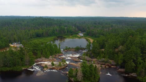 aerial overview of water emptying to gentle cascading waterfalls in conifer riverine forest