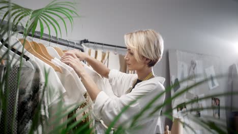 woman tailor choosing clothes in the sewing workshop