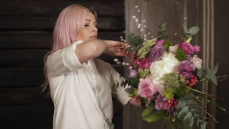 a professional florist tightens the large stems of the bouquet with a string of twine, holding a bouquet in her hands. smiles