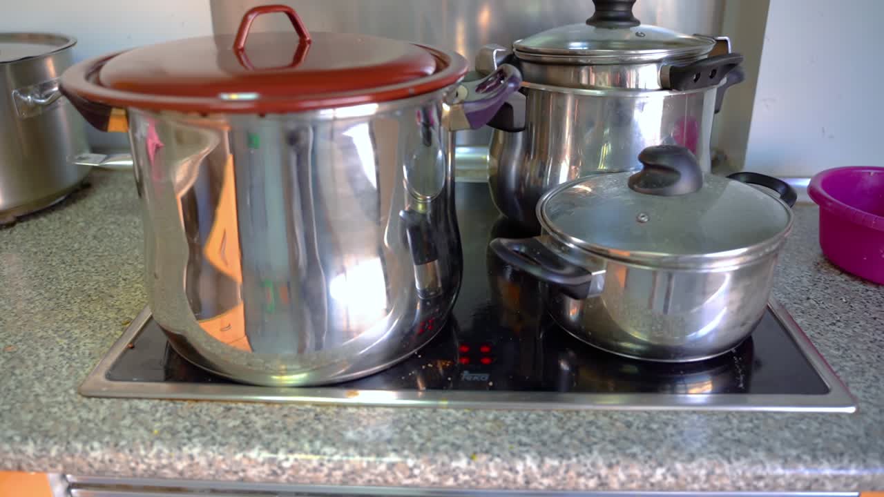 Stainless Pots With Lids On An Induction Cooktop In The Kitchen - close up
