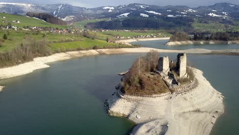 elevación aérea inclinada hacia abajo sobre el lago gruyere y la isla ogoz con los alpes en segundo plano