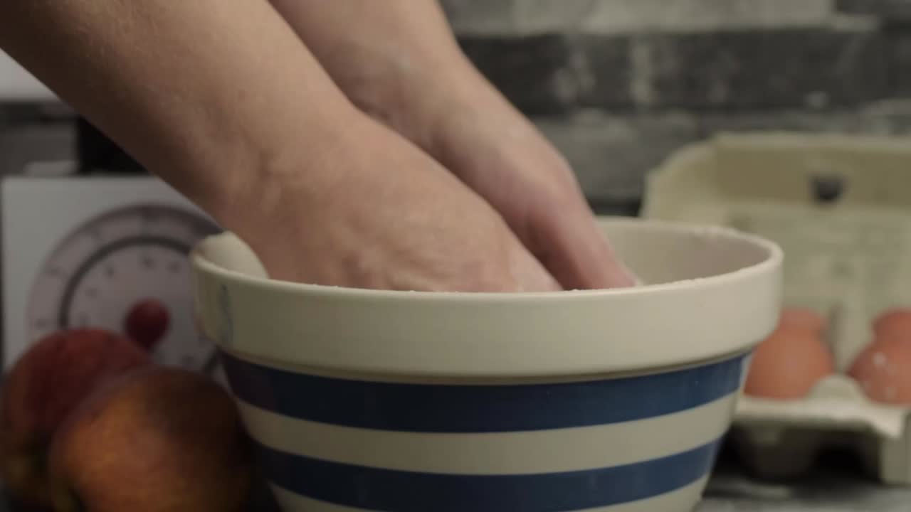 Hands mixing dough in a bowl in kitchen medium shot