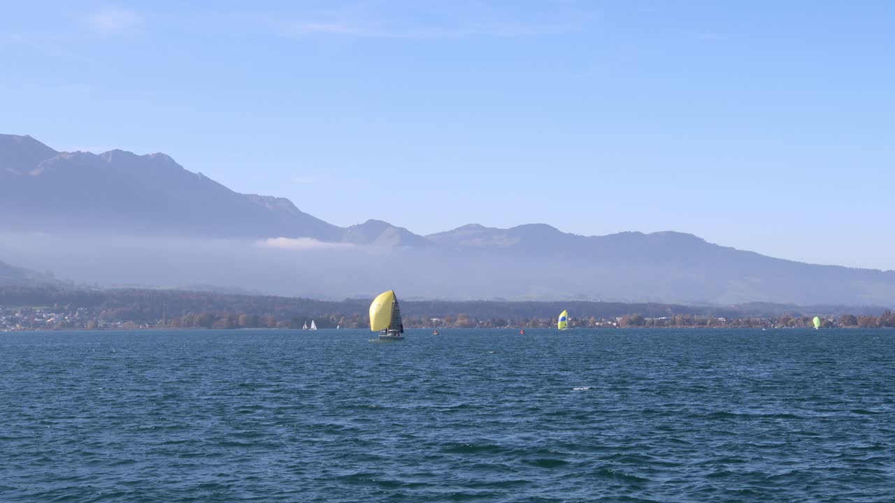 Sailboats sailing across the lake with mountains in the background, establisher