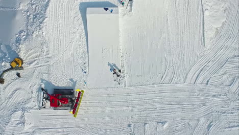 snowplow making ski and snowboard jumps at a ski resort - straight down aerial view