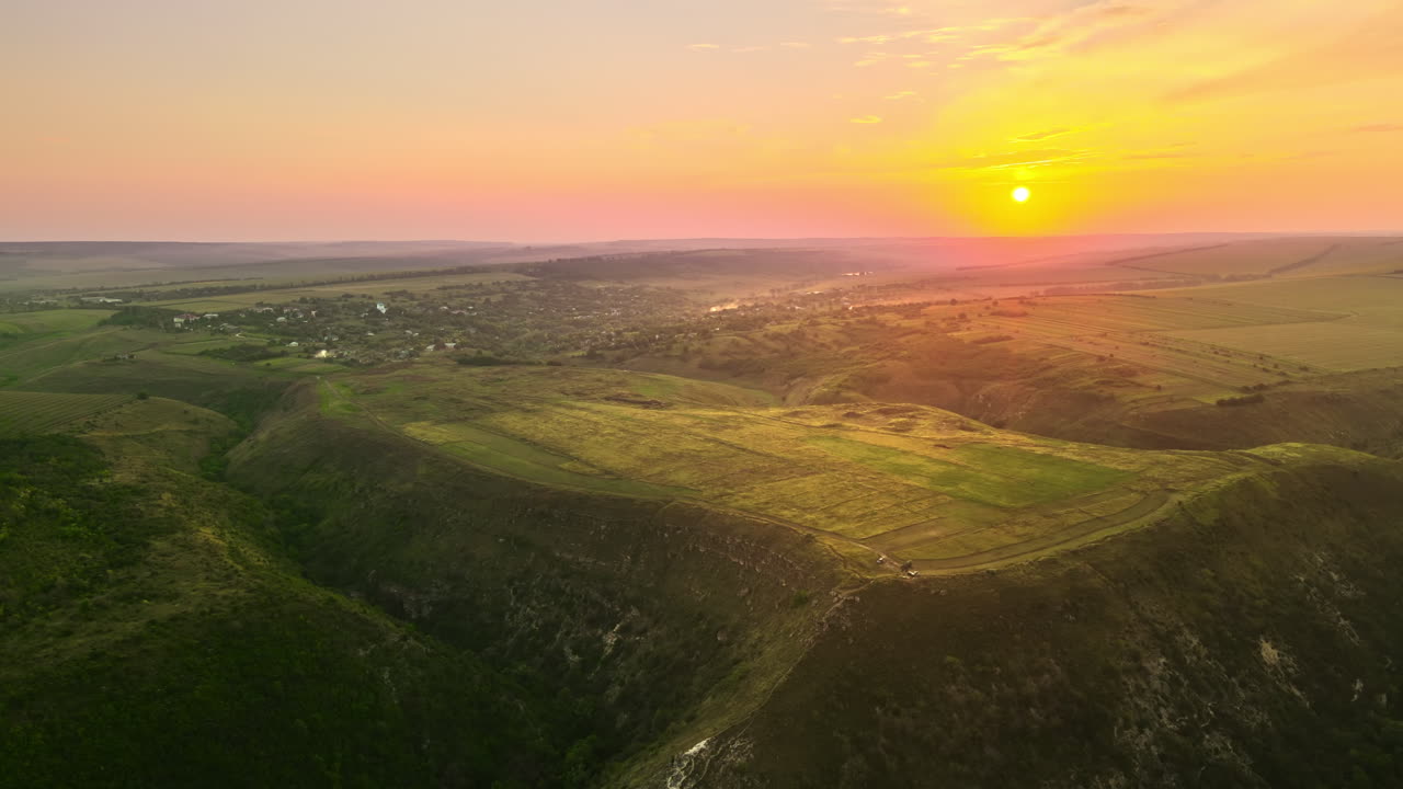 Aerial drone view of nature in Moldova at sunset. Village, sun, fields and hills