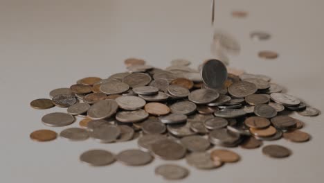 dropping change onto a pile, starting in slow motion and ramped to full speed